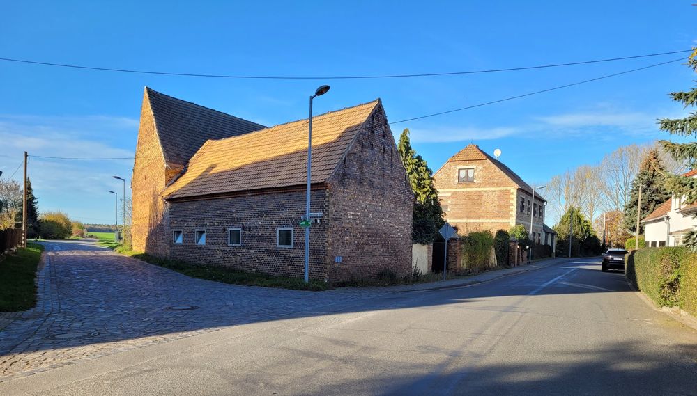 Backsteinscheune an einer Dorfstraße mit Kopfsteinpflaster